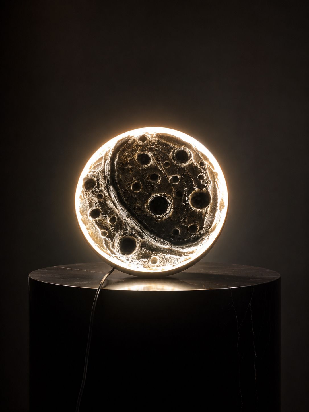 A glowing handmade moon lamp lit against a dark studio backdrop