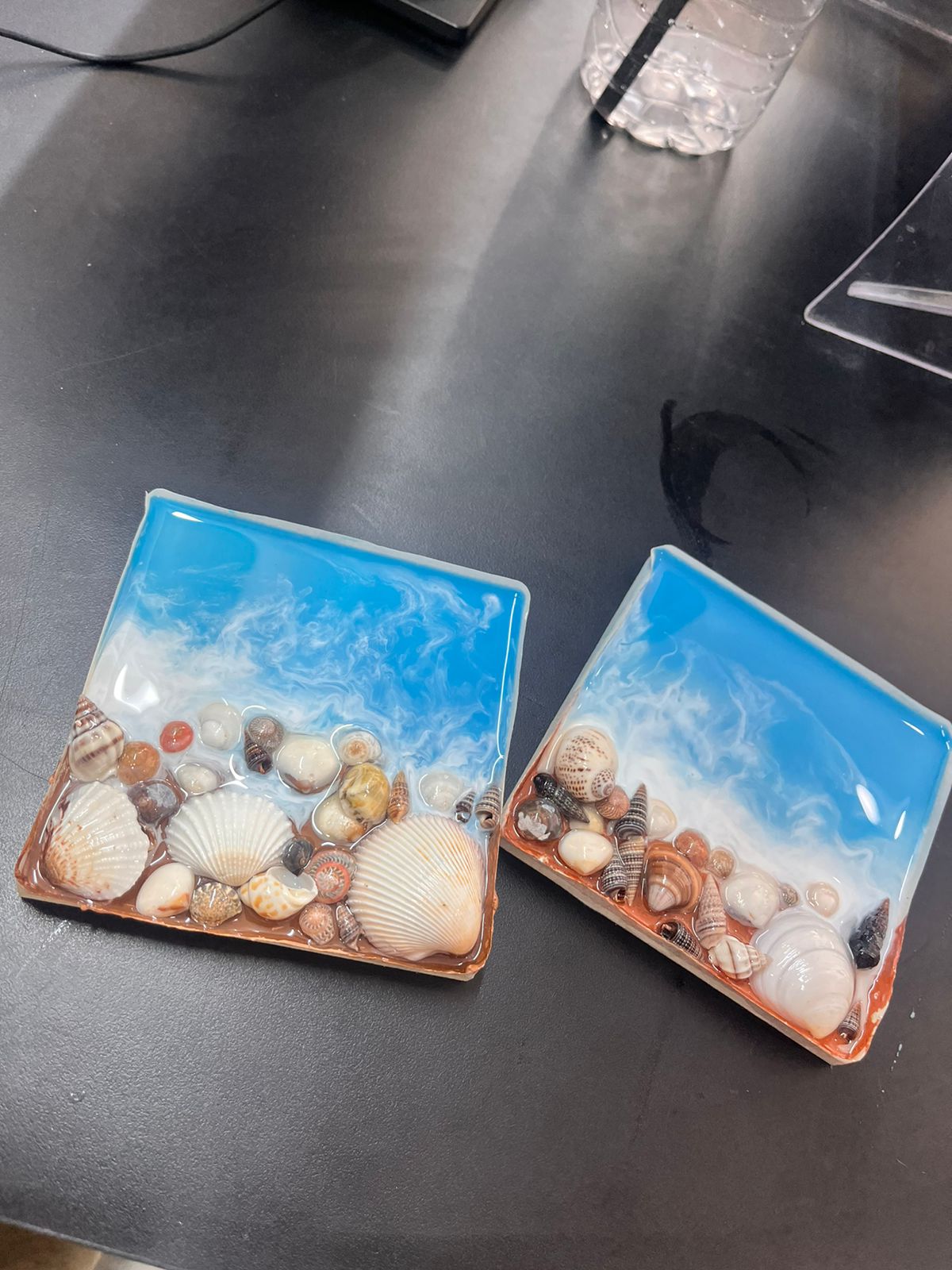A pair of resin ocean tiles drying on the studio table